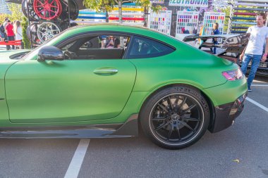 Parlak bitiş ve aerodinamik çizgileri olan orta pozisyonlu, yeşil spor bir arabanın yer aldığı canlı bir araba fuarı sahnesi Aracın gümüş rengi Kyiv, Ukrayna ile siyah tekerlekleri var - 21 Eylül 2025