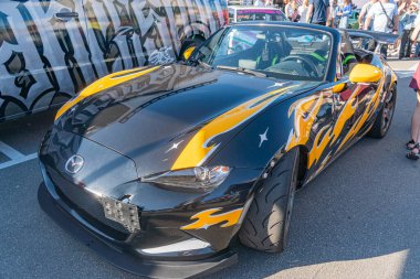 Siyah, sarı, turuncu Mazda Miata marka özel boyalı spor araba, gündüz saatlerinde sokak ya da kamu yolunda fotoğraflanmış yayalar Kyiv, Ukrayna - 21 Eylül 2025