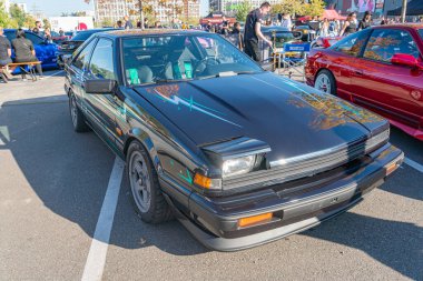 Siyah bir spor araba, açılı, kaput kepçesi ve arka spoiler ile, bir araba fuarında veya buluşmada, açık havada gün ışığında, beton yüzey, renkli pencereler, cu Kyiv, Ukrayna - 21 Eylül 2025