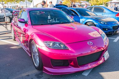 Şehir sokağı, otomobil fuarı, hareketli sahne, birden fazla araba, Mazda Miata üstü açık, açık pembe, keskin hatlar, düz vücut şekli, öne çıkan tampon, Kyiv, Ukrayna 'da büyük hava - 21 Eylül 2025