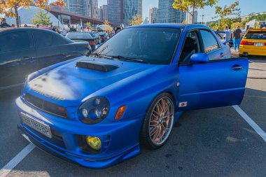 Özel mavi Honda S2000, siyah spoiler, açık sürücü kapısı, şehir sokak arkaplanı, yüksek binalar, sessiz arka planlar, açık gökyüzü, alçak açı perspektifi, c Kyiv, Ukrayna - 21 Eylül 2025