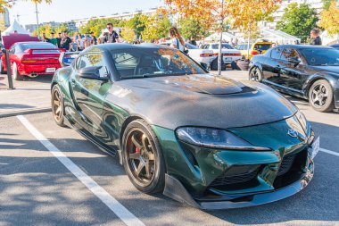 Koyu yeşil Toyota Supra, açık hava araba fuarında geniş bir gövde kiti ve geniş tekerlekler sergiliyor. Etrafı Kyiv, Ukrayna - 21 Eylül 2025