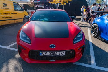 Canlı kırmızı bir Toyota Supra 'nın yakın çekimi, siyah aksanlı, bir otomotiv etkinliğinde ya da buluşmada sergilenmiş, düz bir yüzeye park edilmiş, diğer araçlarla birlikte Kyiv, Ukrayna' da - 21 Eylül 2025