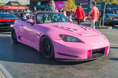 Pembe spor araba, gri asfalta çarpıyor, düşük açılı perspektif, bakımlı ve cilalı, yumuşak gölgeler, geniş doğal ışık, açık hava ayarı, araba fuarı veya Kyiv, Ukrayna - 21 Eylül 2025