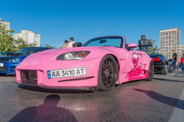 Parlak pembe bir spor araba, muhtemelen Avrupa yarış aracı performans modifikasyonları geniş vücut kiti, arka kanat spoiler, ön ayırıcı, Kyiv, Ukrayna 'da bir açıyla park edilmiş - 21 Eylül 2025