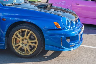 Ukrayna 'nın başkenti Kyiv' de 21 Eylül 2025 'te hafif gelişmiş bir perspektiften gösterilen canlı sokak ortamında spor modifikasyonları ve pembe araçlarla mavi Subaru.