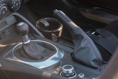 Bir Mazda Miata gösterge panelinin yakın çekimi, sıcak güneş ışığıyla yıkanmış siyah deri direksiyonda yansıyan ışık ve vites kolu görünür basit, fonksiyonel d Kyiv, Ukrayna - 21 Eylül 2025