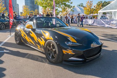 Sarı alevli siyah Mazda Miata, hareketli sokak manzarası, hareketli atmosfer, şehir merkezi veya şehir merkezi, kırmızı bayrak, parlak tasarım, renkli ayrıntı, dinamik ışık Kyiv, Ukrayna - 21 Eylül 2025