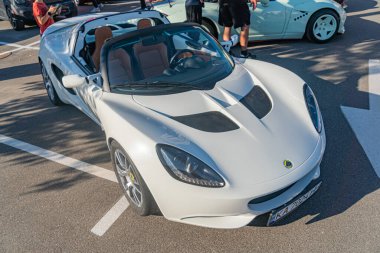 Sokağa park edilmiş beyaz spor araba, şık tasarım, iki açık kapı, aerodinamik çizgiler, siyah aksanlar, düşük ve geniş duruş, yan etekler, arka spoiler, kentsel ortam, Nat Kyiv, Ukrayna - 21 Eylül 2025