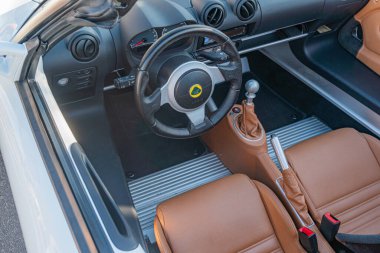 Lüks bir spor arabanın iç mekanı, deri döşemeli koltuklar, dikişli gösterge paneli, farklı direksiyon amblemi ve hafif ışıklandırma Kyiv, Ukrayna - 21 Eylül 2025