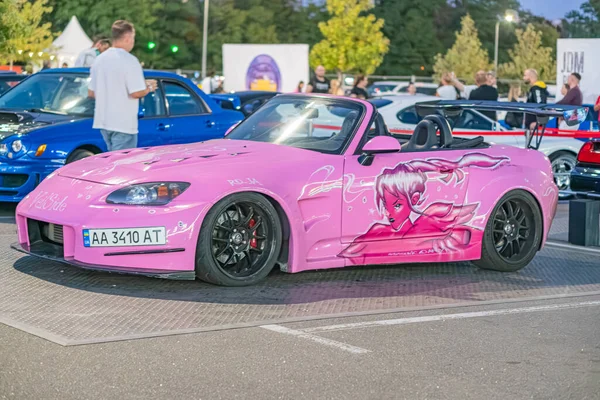 Canlı pembe Mazda Miata, açısal tasarımları ve aerodinamik özellikleri olan modifiye edilmiş spor araba, güneşli bir günde halka açık alana park edilmiş Kyiv, Ukrayna - 21 Eylül 2025