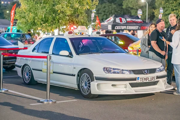 Beyaz, modifiye edilmiş bir Peugeot hatchback ile gece sahnesi asfalta park edilmiş, projektörlerden yapay ışıklandırma sergileniyor Kyiv, Ukrayna - 21 Eylül 2025