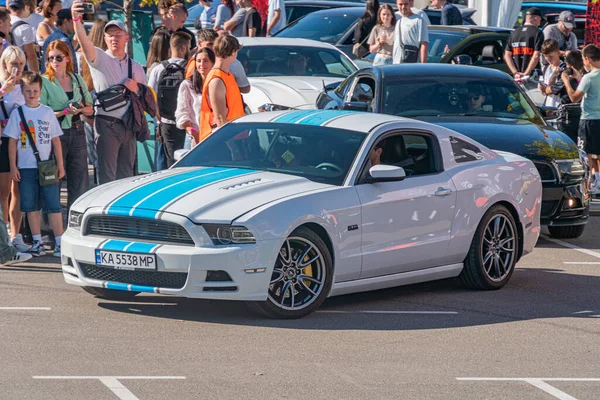 Mavi yarış şeritli beyaz bir Ford Mustang, Shelby GT500 olarak tanımlandı, şehir merkezinde bir açıya park edilmiş, muhtemelen bir araba fuarı sırasında ya da karşılaşma sahnesi Kyiv, Ukrayna - 21 Eylül 2025