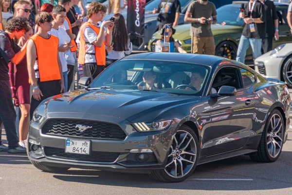 Özet Gri Ford Mustang, Ukrayna 'nın başkenti Kyiv' de 21 Eylül 2025 'te bir otomotiv etkinliği sırasında insanlarla çevrili olarak sokağa park edildi.