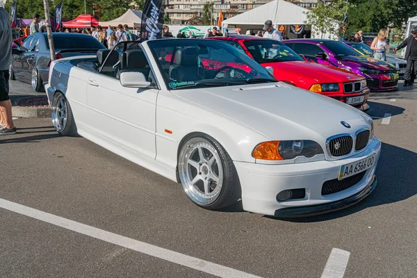 Otoparkta araba fuarı, ön planda beyaz BMW Z3, arka planda gelişigüzel park edilmiş diğer arabalar, etrafta dolaşan insanlar, doğal fotoğrafçılık tarzı, açık park yeri Kyiv, Ukrayna - 21 Eylül 2025
