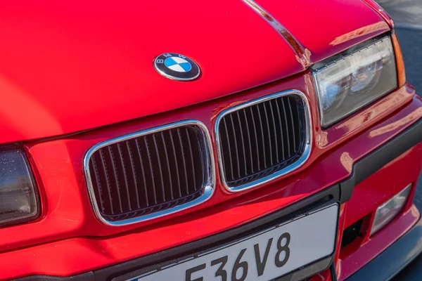 BMW amblemi ile ızgarasına odaklanan kırmızı bir BMW 'nin yakın plan görüntüsü görülebilir farlar ve kaputun üzerindeki E6V 8 yansıması güneş ışığı veya e Kyiv, Ukrayna - 21 Eylül 2025