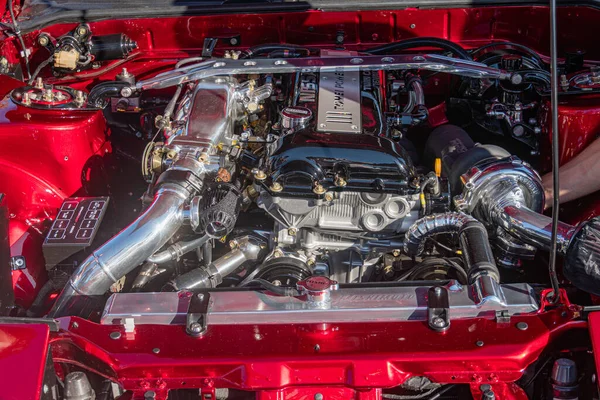 Açık kırmızı bir araba motorunun yakın plan görüntüsü, ağırlıklı olarak metalik elementlerle kırmızı. Büyük gümüş emme manifoldu, yılan boruları ve hortumlar, statik ve hareketli eş Kyiv karışımı, Ukrayna - 21 Eylül 2025