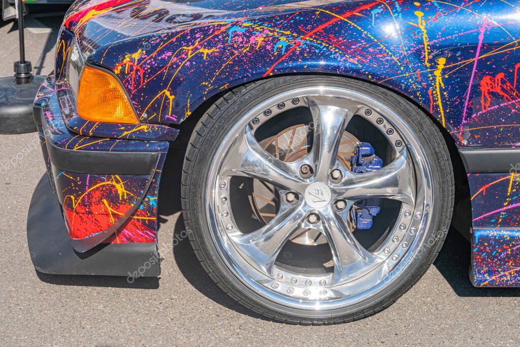 Vibrant blue-red BMW with glossy finish, showcasing its silver wheel with multiple spokes on asphalt Kyiv, Ukraine - September 21, 2025