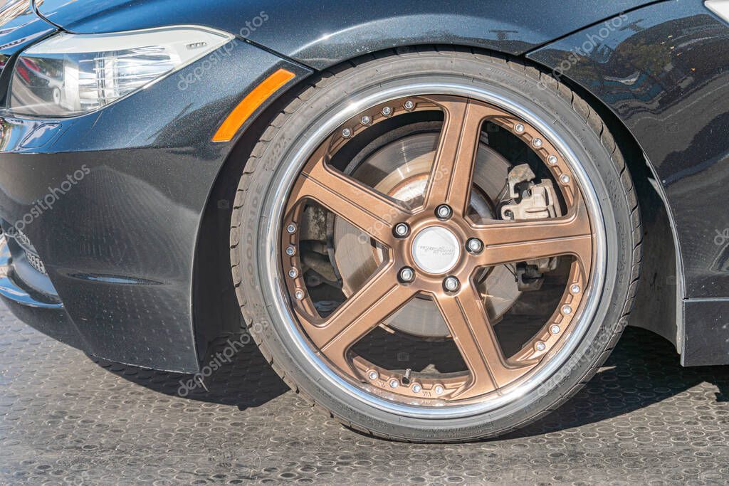 Close-up of a three-quarter BMW car wheel, silver multi-spoke alloy with branded center cap, dark blue bodywork, soft natural lighting, visible tire and lug nuts, re Kyiv, Ukraine - September 21, 2025