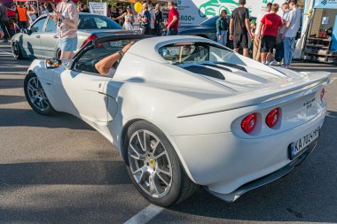 Kalabalık bir otoparkta beyaz spor araba, hafif açık yolcu kapısı, kırmızı fren ayarlı parlak tasarım, gümüş alaşımlı tekerlekler, arka spoiler, doğal gündüz lig Kyiv, Ukrayna - 21 Eylül 2025