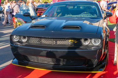 Kırmızı halıda siyah bir Dodge Charger SRT Hellcat, parlak dış ışık ve bulanık figürlerle çevrili bir çevre ışığıyla karşımıza dikildi ve Ukrayna, Kyiv, Ukrayna - 21 Eylül 2025