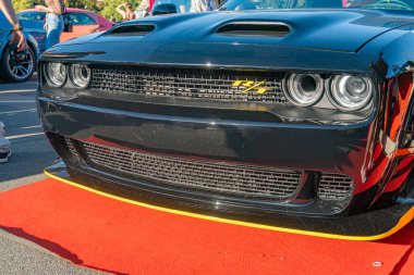 Siyah Dodge Challenger turuncu yarış şeritleri, kaput ve yan kepçeleri, belirgin ızgara logosu, kırmızı halıya park edilmiş, gösteri ya da olay yeri, sol Shadowin Kyiv, Ukrayna - 21 Eylül 2025
