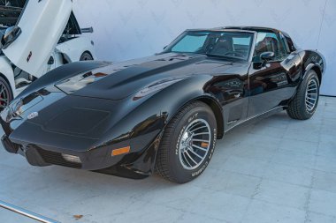 Siyah kaslı Corvette kapalı bir otomobil fuarında ya da etkinlikte sergileniyor, merkezi olarak sağa bakan bir ön cephe, kalın tasarım yuvarlak far, büyük ızgara, b Kyiv, Ukrayna - 21 Eylül 2025
