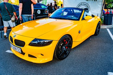 Sarı BMW i8, siyah çatı ve siyah jant plakalı canlı şehir sokak sahnesi BMW 160 Beton kaldırım, bulanık yayalar, doğal gün ışığı, Kyiv, Ukrayna - 21 Eylül 2025