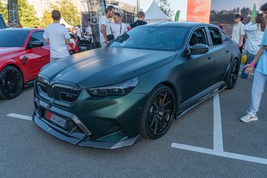 Siyah modifiye edilmiş BMW M modelinin yer aldığı kapalı araba fuarı geniş ızgaralı, kaputlu, arka kaputlu ve siyah tekerlekli Kyiv, Ukrayna - 21 Eylül 2025