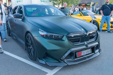 Beyaz işaretli siyah BMW yarış arabası, farklı mesafeden farklı giysiler giyen insanlar, farklı renklerde farklı renklerde insanlar, dept Kyiv, Ukrayna - 21 Eylül 2025