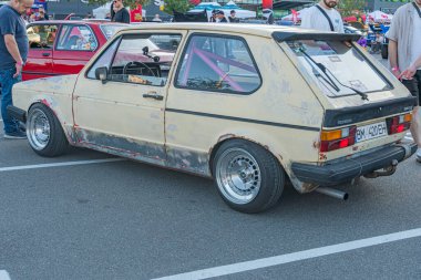 Otoparkta sergilenen eski Volkswagen Golf yarış arabası, soluk sarı gövde ve siyah yarış çizgileri ile çatı çizgisini indirdi, açık motor bileşeni Kyiv, Ukrayna - 21 Eylül 2025