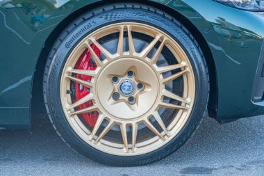 Spor araba tekerleğinin yakın çekimi, çok dilli desenli gümüş alaşımlı jantlar, belirgin olmayan dairesel marka amblemi, canlı kırmızı fren kalibreli, tepeden tırnağa Kyiv, Ukrayna - 21 Eylül 2025