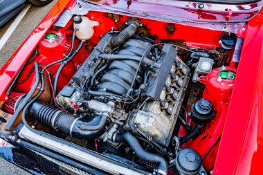 Açık araba kaputu, motor bölümünü hortumlar, borular, hava emme sistemi, soğutma deposu ve diğer sıvı hatları ile gösteriyor. Metalik bileşenler, Ukrayna 'nın başkenti Kyiv' de 21 Eylül 2025 'te odaklanmış aydınlatma altında parlıyor.