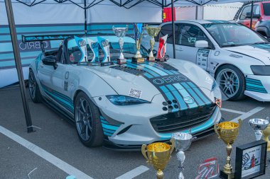 Açılır kapanır bir çadırın altında, kupalarla çevrili mavi ve beyaz bir yarış arabası, bir etkinlikte asfaltlı bir yüzey üzerinde ya da Kyiv, Ukrayna - 21 Eylül 2025