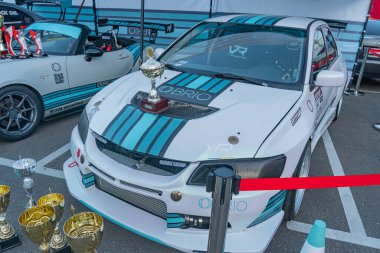 Mavi ve siyah çizgili beyaz yarış arabası, büyük arka kanat, muhtemelen Formula 1 veya açık teker yarış kategorisinde araç, kapalı alanda garaj odası, kupalar lin Kyiv, Ukrayna - 21 Eylül 2025