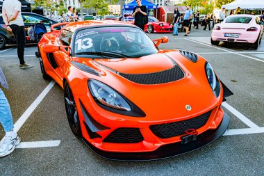 Kırmızı renkli spor araba, geniş spoiler ve beyaz çizgili park alanında öne çıkan ön tampon ile siyah aksanlı, Ukrayna 'nın s Kyiv kentindeki diğer araçlarla çevrili - 21 Eylül 2025