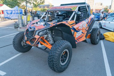 Turuncu arazi aracı ATV, geniş lastikler ve turuncu grafiklerle ön plana çıkarak Ukrayna 'nın yumuşak gölgesi Kyiv ile gündüz yakalanır.