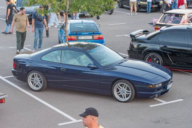 Benzersiz arabalarla çevrili beyaz bir alana park edilmiş mavi bir BMW Z4 'ün yer aldığı açık hava araba fuarı sahnesi, Natur Kyiv, Ukrayna - 21 Eylül 2025