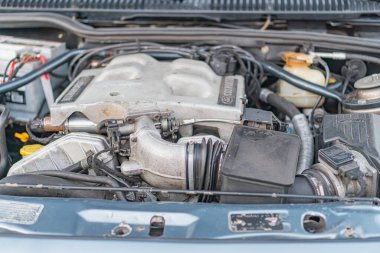 Bir araba motoru kompartımanının yakın çekim görüntüsü, emniyet kemerleri, borular ve elektrik bağlantıları gibi iç yanmalı motor bileşenlerini gösteren motor kapağı kısmi Kyiv, Ukrayna - 21 Eylül 2025