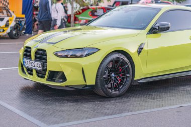 Otoparktaki sarı BMW araba, doğal ışık altında parlıyor. Aerodinamik tasarım ve etrafındaki bulanık arabalar yoğun bir olay olduğunu gösteriyor. Ya da ağırlıklı olarak sarı renkli bir Kyiv, Ukrayna - 21 Eylül 2025