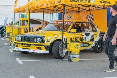 Klasik sarı yarış arabası, BARDahl markası, aerodinamik tasarım, alevli tekerlek kemerleri, modern sarı yarış arabası taşıyıcısı, dama tahtası grafikleri, BARDahl bran Kyiv, Ukrayna - 21 Eylül 2025