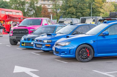 Canlı park yeri, üç farklı araba mavi, pembe ve yeşil, her biri 21 Eylül 2025 'te Ukrayna' nın başkenti Kyiv 'in altında siyah jantlı ve tamamlayıcı renk aksanlı benzersiz bir stil sergiliyor.