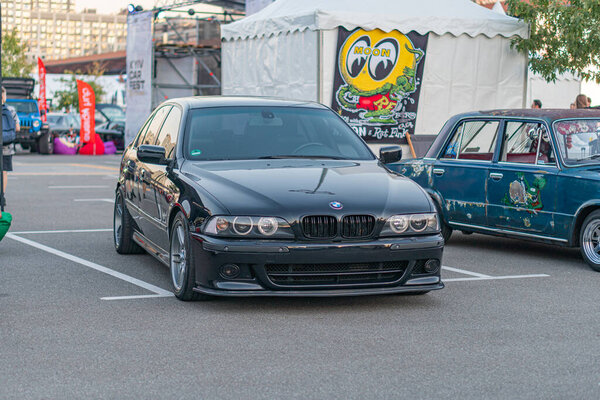 Выставка автомобилей на открытом воздухе, черный BMW 3 Серия глянцевая отделка, пользовательский комплект кузова, синие фары, синие колеса, версия трека намеки неокрашенный капюшон, видимые заклепки, частичный vi Киев, Украина - 21 сентября 2025