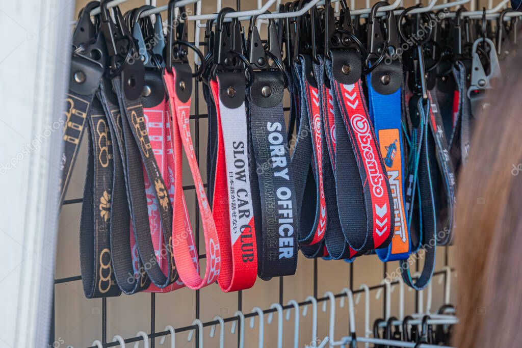 Collection of car brand logo souvenir lanyards hanging vertically against a beige background, varying in design, size, and color reds, blues, blacks, whites, with Kyiv, Ukraine - September 21, 2025