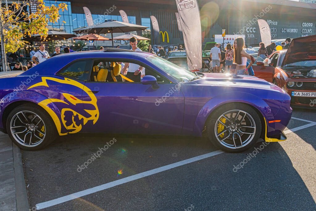Summary Vibrant car show scene featuring a custom purple muscle car with orange lion design, colorful modifications, bright outdoor setting, festive atmosphere, Kyiv, Ukraine - September 21, 2025