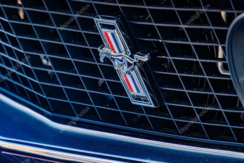 Close-up view of a sleek, dark Ford Mustang with silver accents Prominent galloping horse and wings logo on grille Intricate horizontal bars design on the grille Kyiv, Ukraine - September 21, 2025