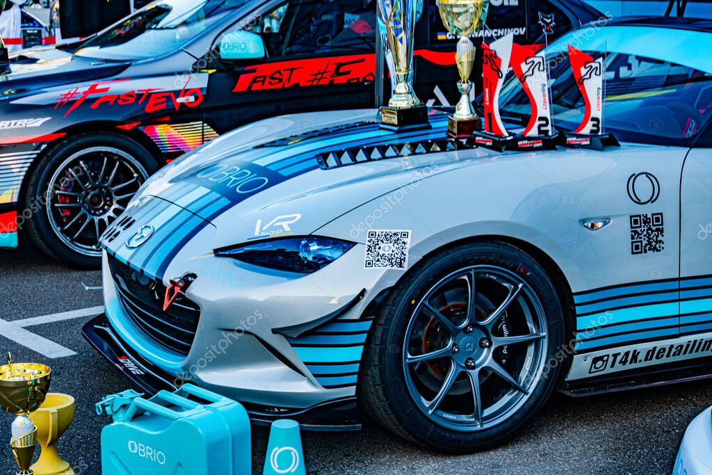 Indoor car show featuring a vibrant blue sports car with decals and logos, possibly a racing vehicle or high-performance model Several other cars are on display, on Kyiv, Ukraine - September 21, 2025