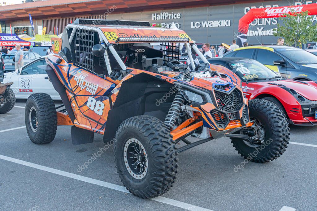 Indoor off-road vehicle exhibition Orange Honda quad bike, with black accents and sponsor logos, parked against uniform flooring and structured ceiling Modern, ang Kyiv, Ukraine - September 21, 2025