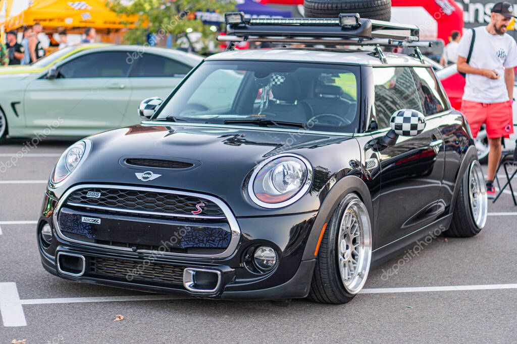 Black Mini Cooper car with a sporty spoiler parked at an angle, featuring circular headlights and modified rims Sleek bodywork reflecting light, against a backdrop Kyiv, Ukraine - September 21, 2025