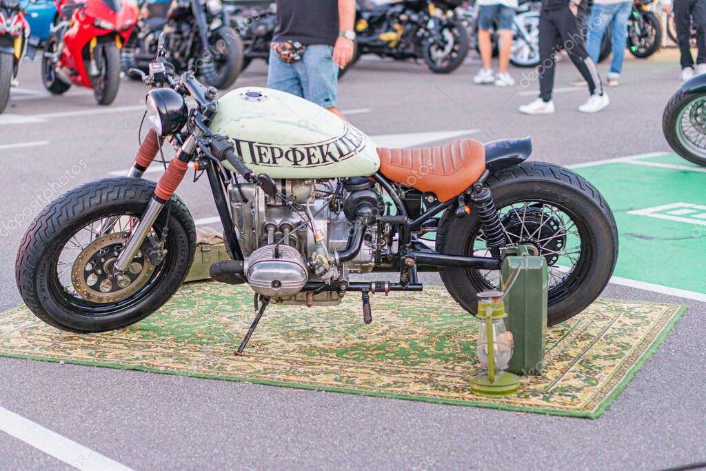 Vintage Harley-Davidson motorcycle displayed at an outdoor event, painted light cream with black details and a HOPPER logo Positioned on a colorful oriental rug in Kyiv, Ukraine - September 21, 2025